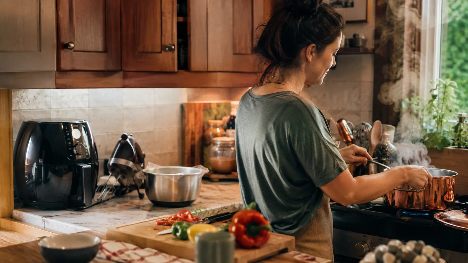 A bright, tidy home kitchen counter with a wooden cutting board, fresh vegetables, and everyday kitchen gadgets