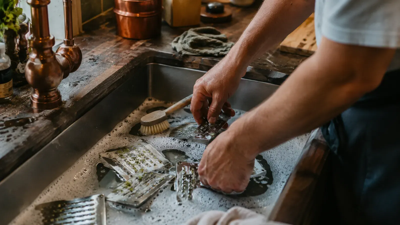 Sink full of spiralizer blade attachments soaking in soapy water with pulp caught in the blade teeth